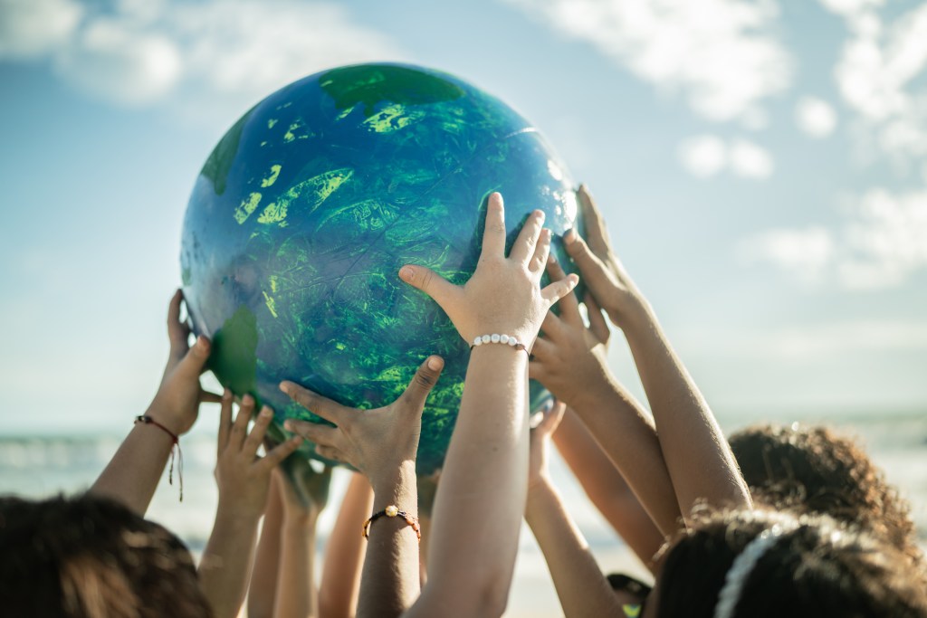 Close-up of children holding a planet at the beach