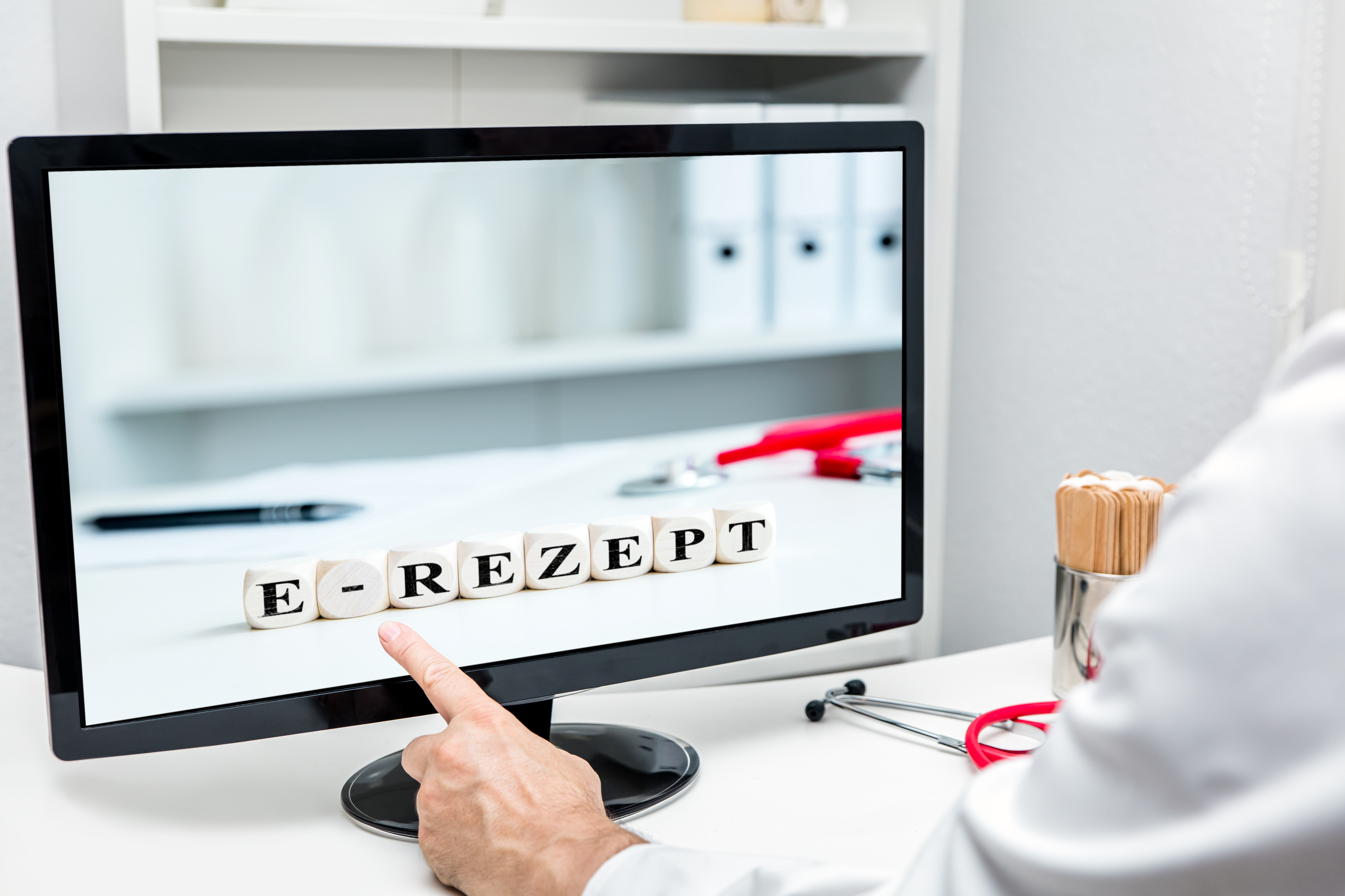 Arzt zeigt auf Monitor mit der Aufschrift e-Rezept